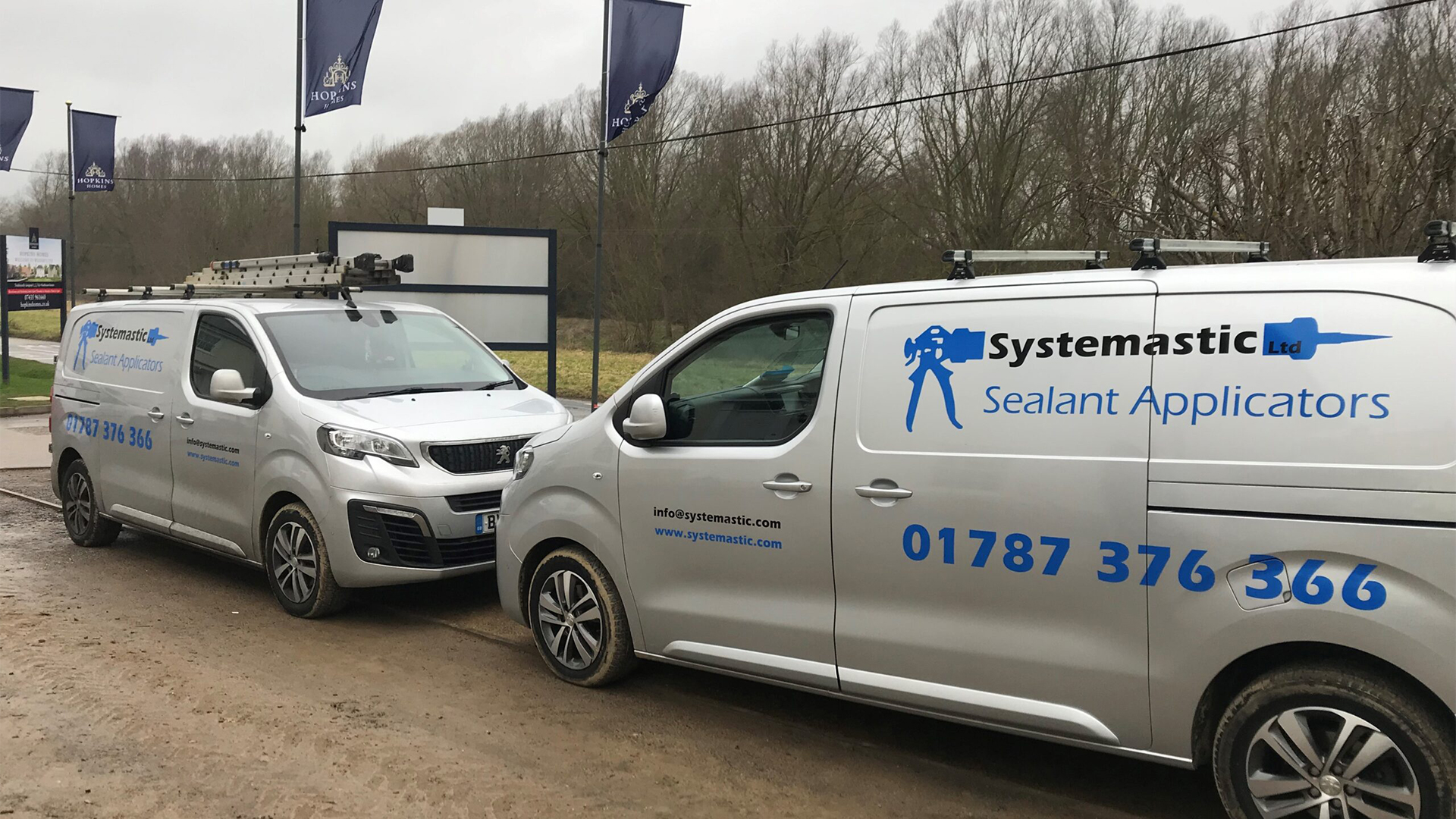 Two vans with Systemastic branding in front of building