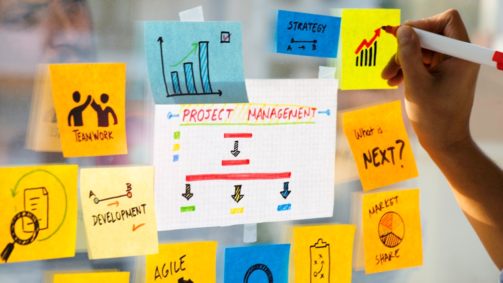 Selection of post it notes on glass with key words relating to project management